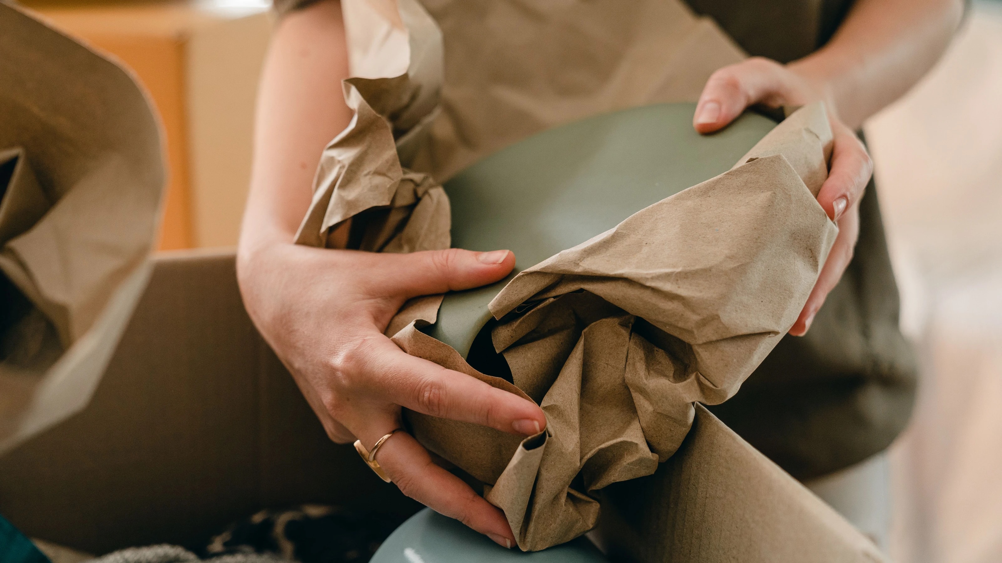 Carefully wrapping a plate in packing paper